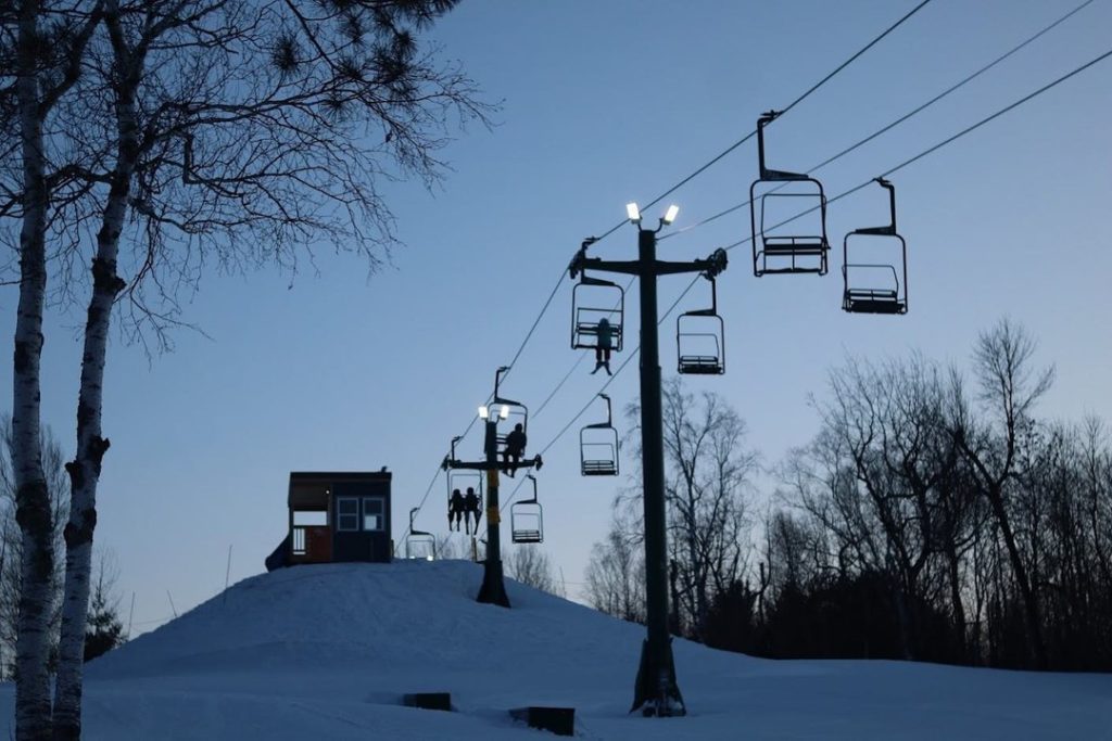 Chairlift lights are visible in front of a darkening ski hill.